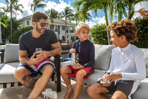 Dad and two boys sitting by the pool