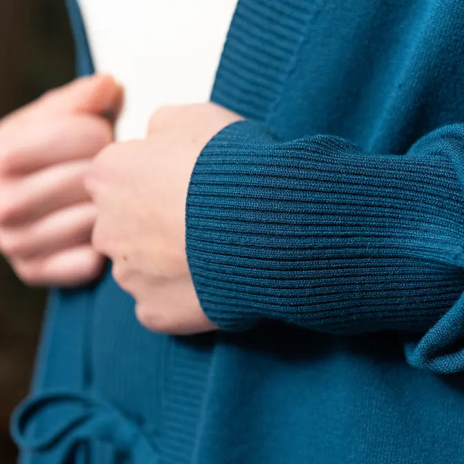 A close up of the rib cuff detail of a woman showcasing the Women's Callie Long Sleeve Front Tie Sweater paired with a white shirt