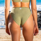 Back of a woman in a sage green bikini in front of the ocean