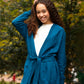 The Women's Callie Long Sleeve Front Tie Sweater in blue worn by a female model outside in a park