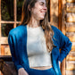 Women's Camille Ribbed Crop Top in an ivory color shown with the blue Callie Front Ties Sweater on a woman in front of a cabin