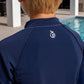 Back of Boy by the pool wearing a blue long sleeve rash guard designed for swimming