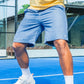 Men's blue Haven Swim Trunks paired with a yellow polo on a tennis court for a sporty look