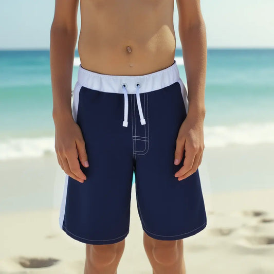 Boy in blue swim trunks from the waist down in front of the ocean