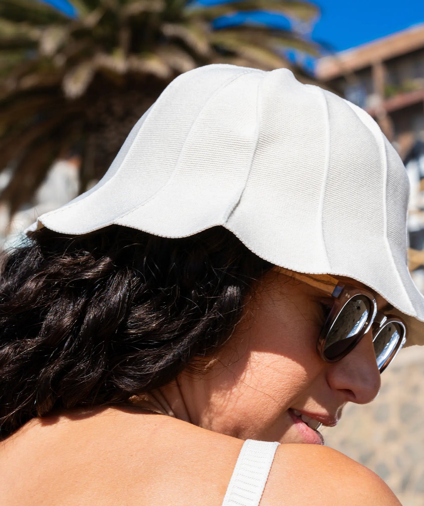 Side of womans face wearing hat and sunglasses at the beach